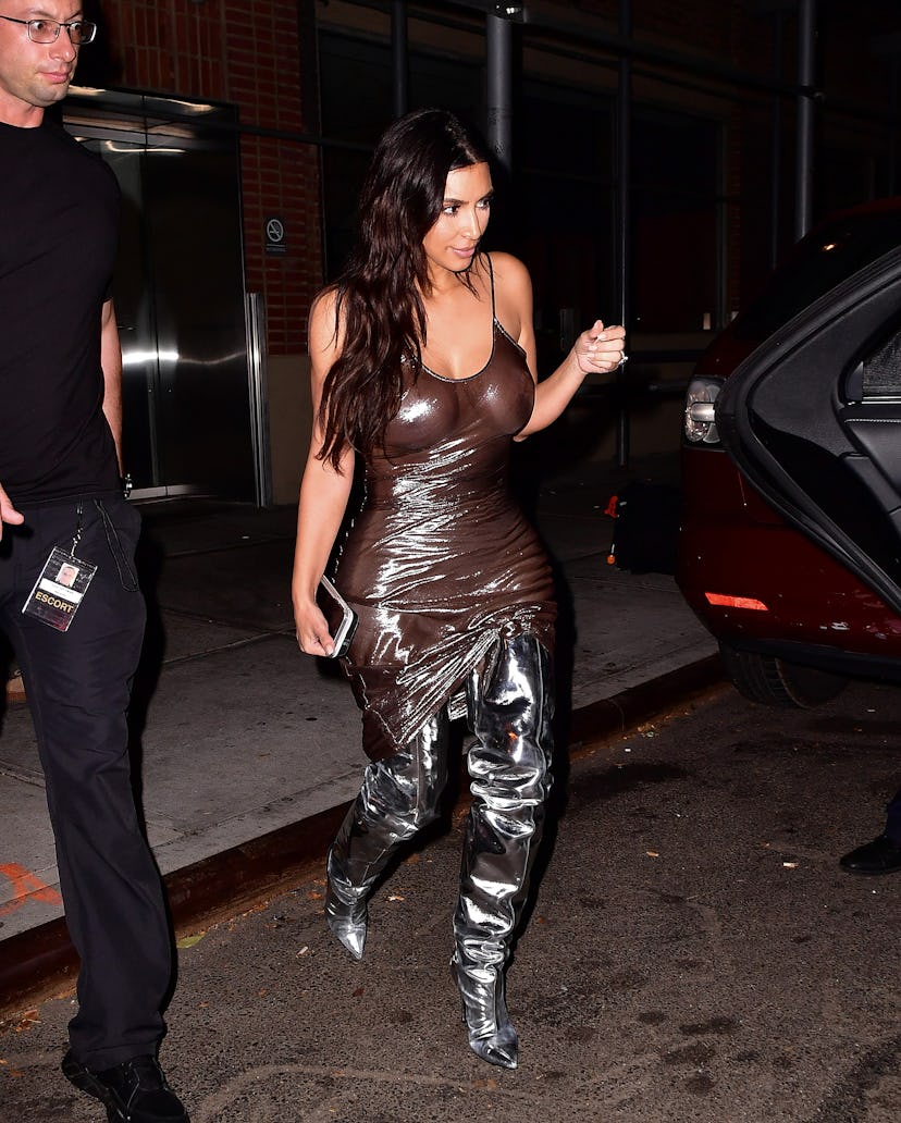 Kim Kardashian wears a shiny slip dress and metallic silver slouchy boots in 2016.