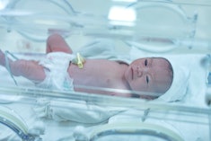 Capturing the delicate first day of a newborn baby lying down in an incubator, experiencing the care...