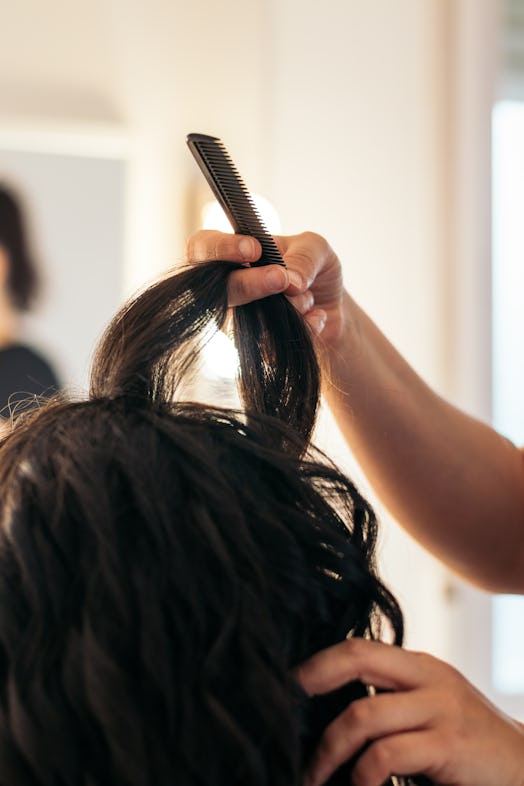 Close-up of a hairdresser combing an unrecognizable person's hair.