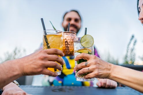 Young cheerful friends drinking cocktails and enjoying time together at the bar