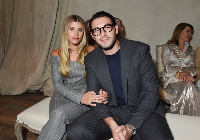 Sofia Richie wears gray pinstripe co-ords, a black handbag, and white pointed pumps with Elliot Grai…