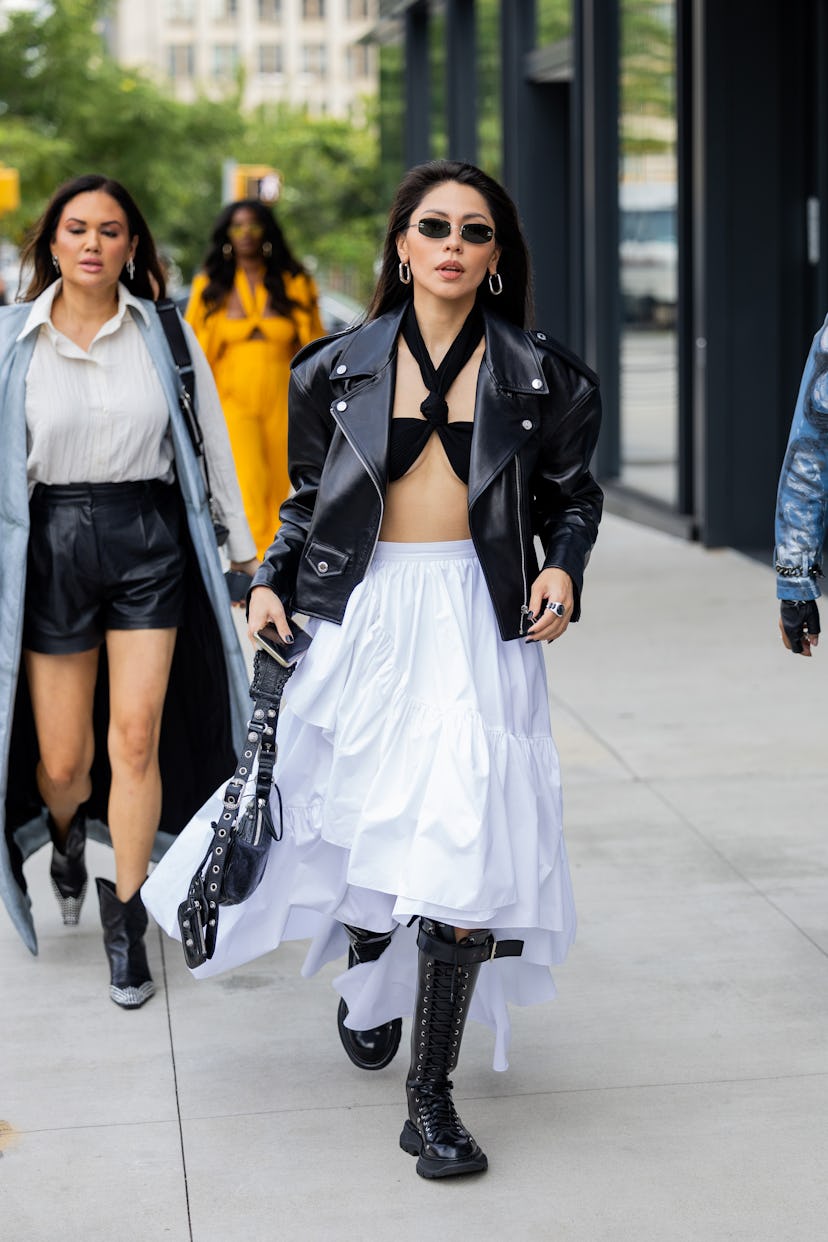 NEW YORK, NEW YORK - SEPTEMBER 09: A guest wears black leather jacket, white skirt, Balenciaga bag o...