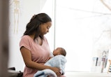 In the doctor's examination room, the depressed young adult mother looks down at her baby in her arm...