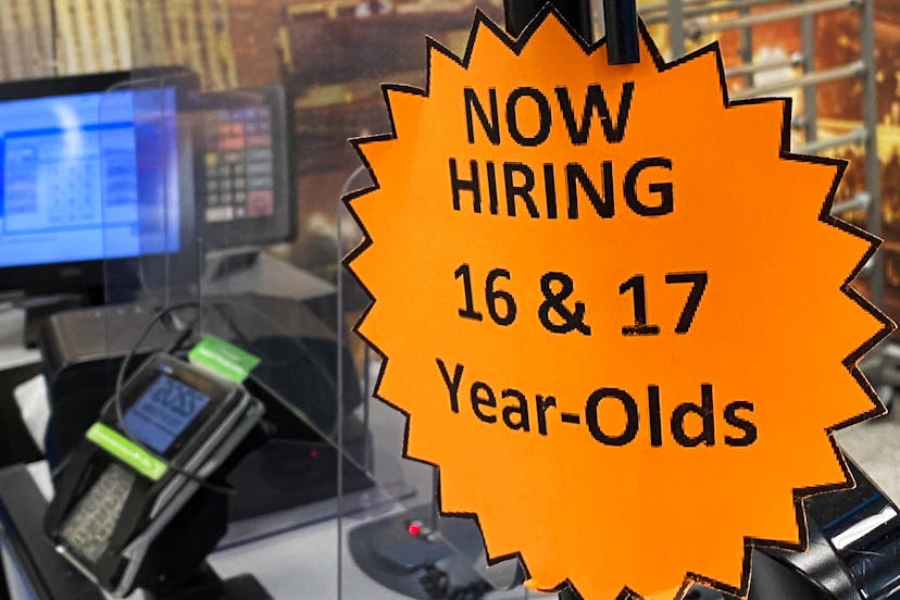 Signage advertising now hiring for 16 and 17 year old employees is displayed on a cash register insi...
