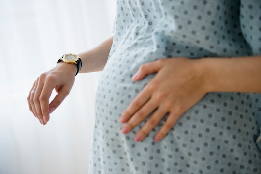Pregnant woman in hospital down touches her belly, in a story answering the question, what is fetal ...