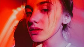 Photo of a young woman posing under the neon lights.