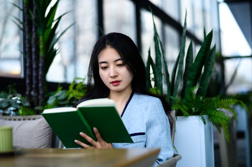 Asian young woman reading book in coffee shop