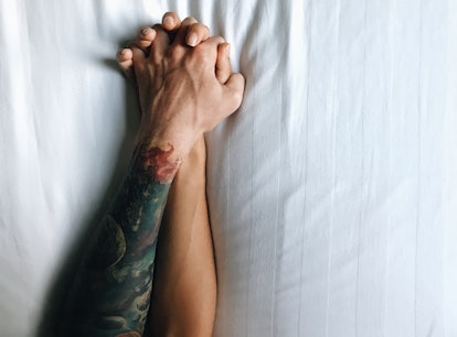 a couple holds hands as they explore the kink they should try, based on their zodiac sign