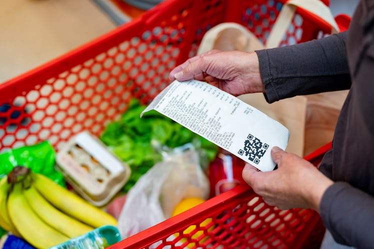 Close up of unrecognizable customer checking her receipt after purchasing groceries in the supermark...