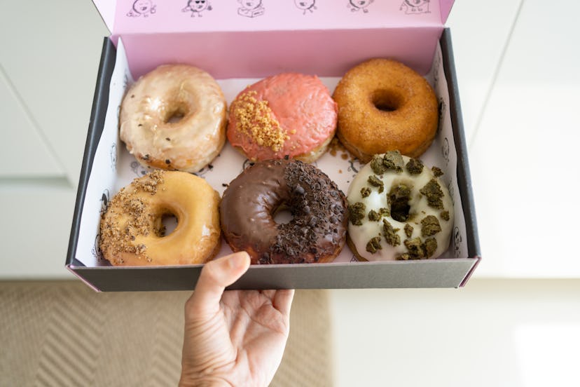 Woman`s hand holding box with doughnuts, close-up
