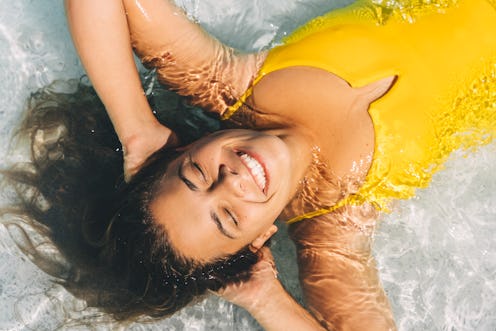 Beautiful woman in yellow swimsuit lies on transparent sea water on a summer sunny day. The concept ...