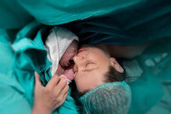 Mother kisses her newborn during C-section, in a story about C-section birth videos.