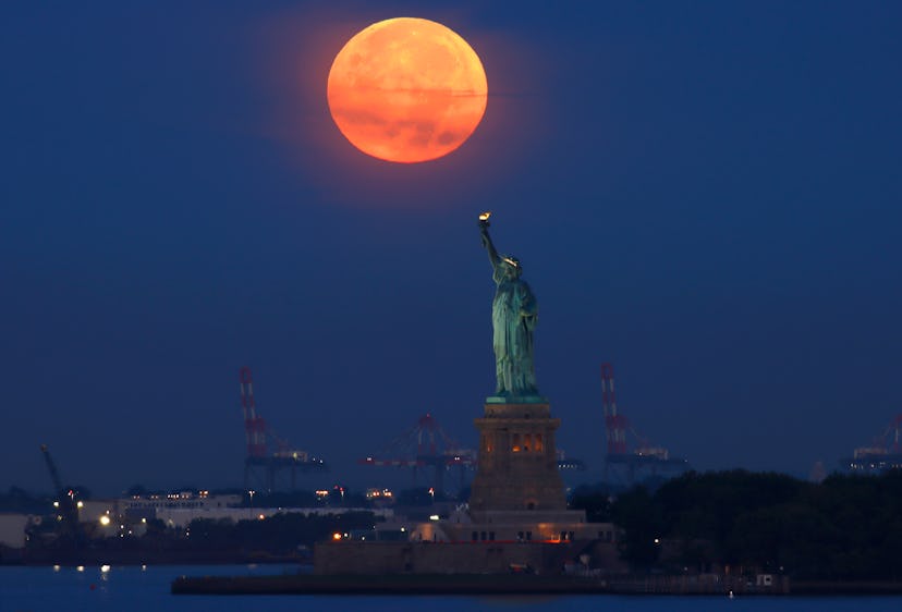 NEW YORK, NY - SEPTEMBER 10:  The full Harvest Moon sets behind the Statue of Liberty as the sun ris...