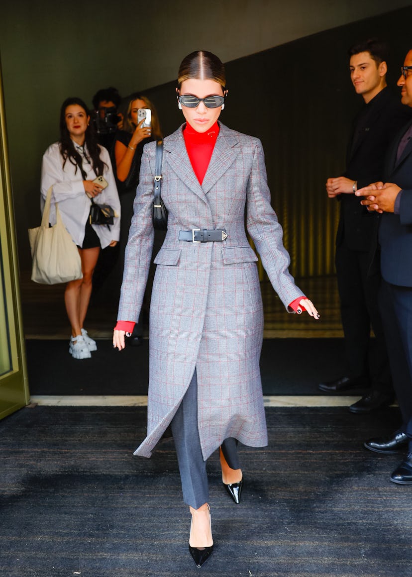 Sofia Richie wears a Prada coat, trousers, turtleneck top, and accessories to the Prada show during ...