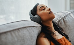 Shot of a young woman using headphones listening to songs about miscarriage