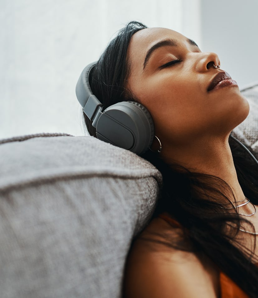 Shot of a young woman using headphones listening to songs about miscarriage