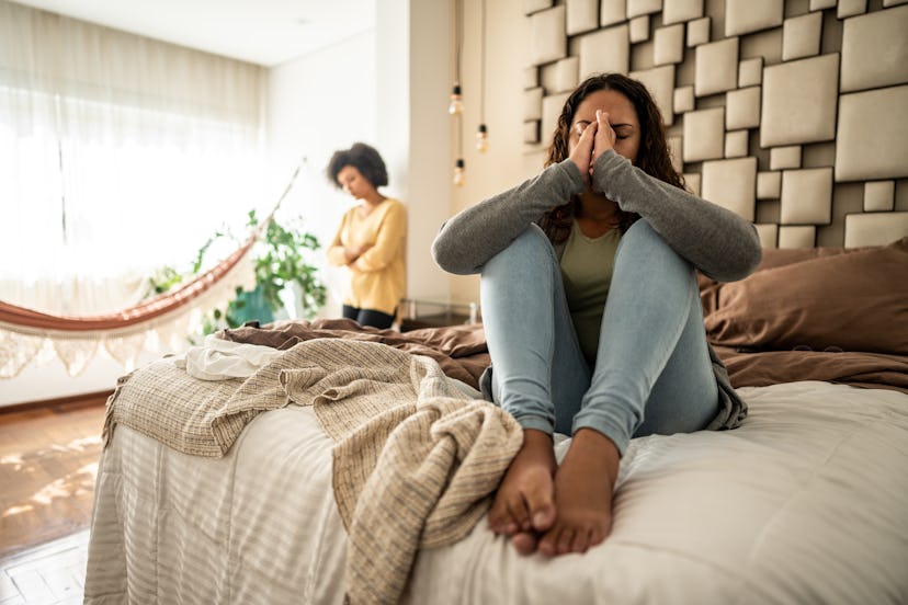 Worried young woman sitting on bed in the bedroom at home