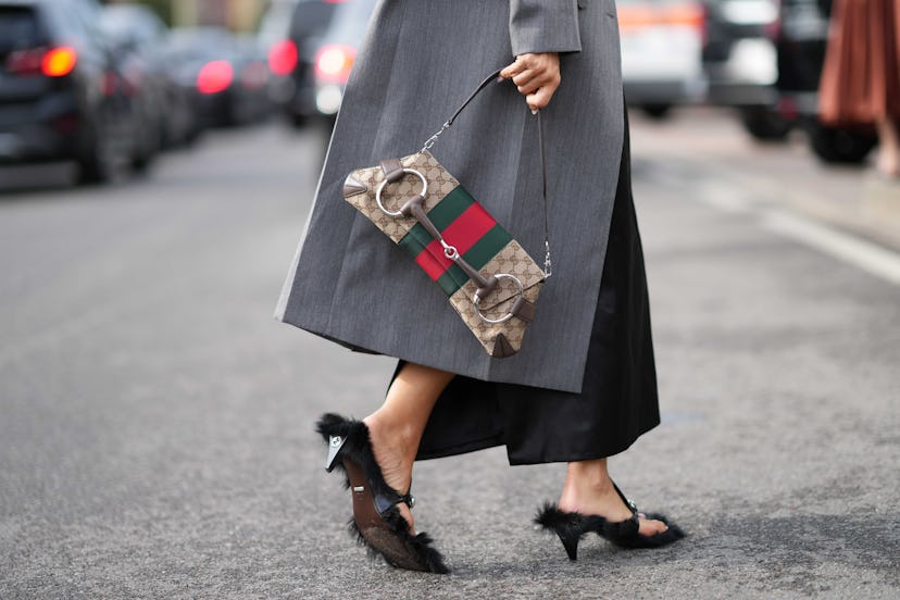 An attendee wears black silk lustrous pants,  fluffy shoes , a Gucci bag, outside Gucci, during the ...