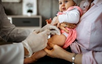 Baby getting a shot in her leg at the doctor's office, in a story about why it's so hard to find Cov...