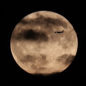 NEW JERSEY, USA - OCTOBER 1: A plane flies through as The Harvest Moon rises behind The Statue of Li...