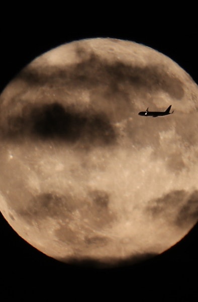 NEW JERSEY, USA - OCTOBER 1: A plane flies through as The Harvest Moon rises behind The Statue of Li...