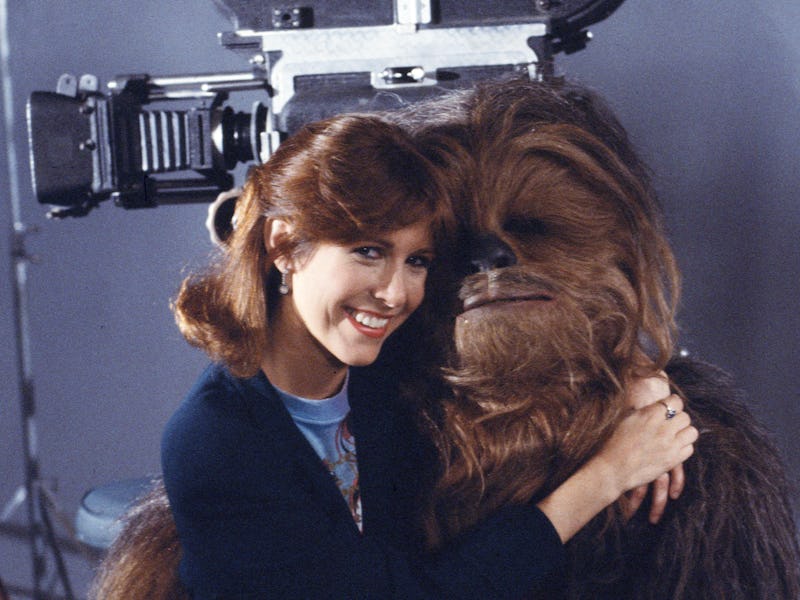 Promotional portrait of American actress Carrie Fisher as she sits on the lap of British actor Peter...
