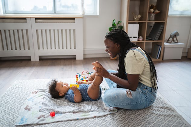 Mother Black ethnicity doing exercise for hip dysplasia prevention on her baby boy