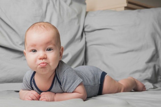 Funny portrait of newborn baby 4 months old on bed