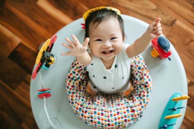 Directly above shot of adorable Asian baby girl having fun playing in activity centre at home, looki...