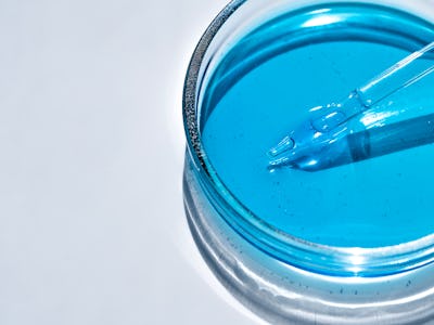 Blue facial serum in petri dish on white background. Cosmetic and medicine concept. Laboratory glass...