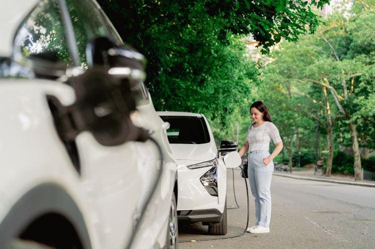Woman charging her electric car in a park.