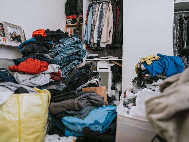 A messy bedroom during the change of wardrobe. Many clothes on the bed.