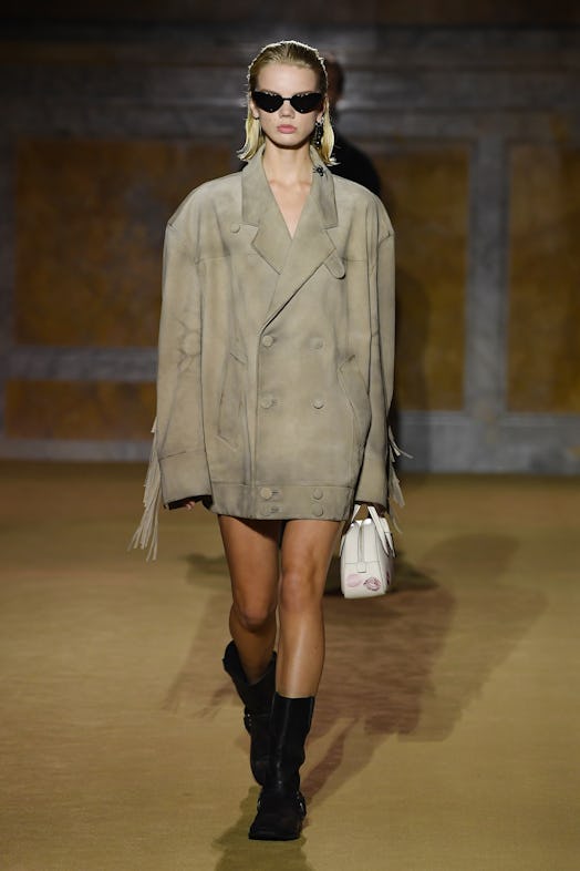 A model wearing a boxy suede jacket on the COACH Spring 2024 runway.