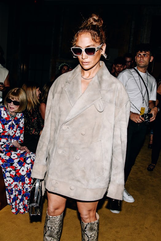 Jennifer Lopez wears a suede jacket, snakeskin boots, and a Coach Tabby bag at the COACH Spring 2024…