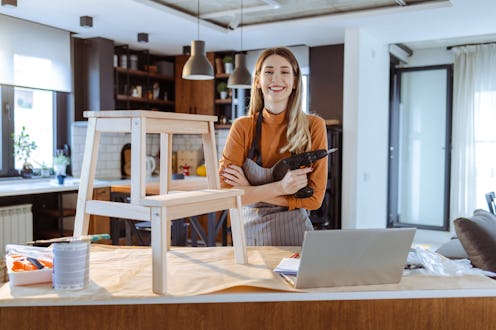 Young woman wearing an apron and assembling furniture at home. DIY concept