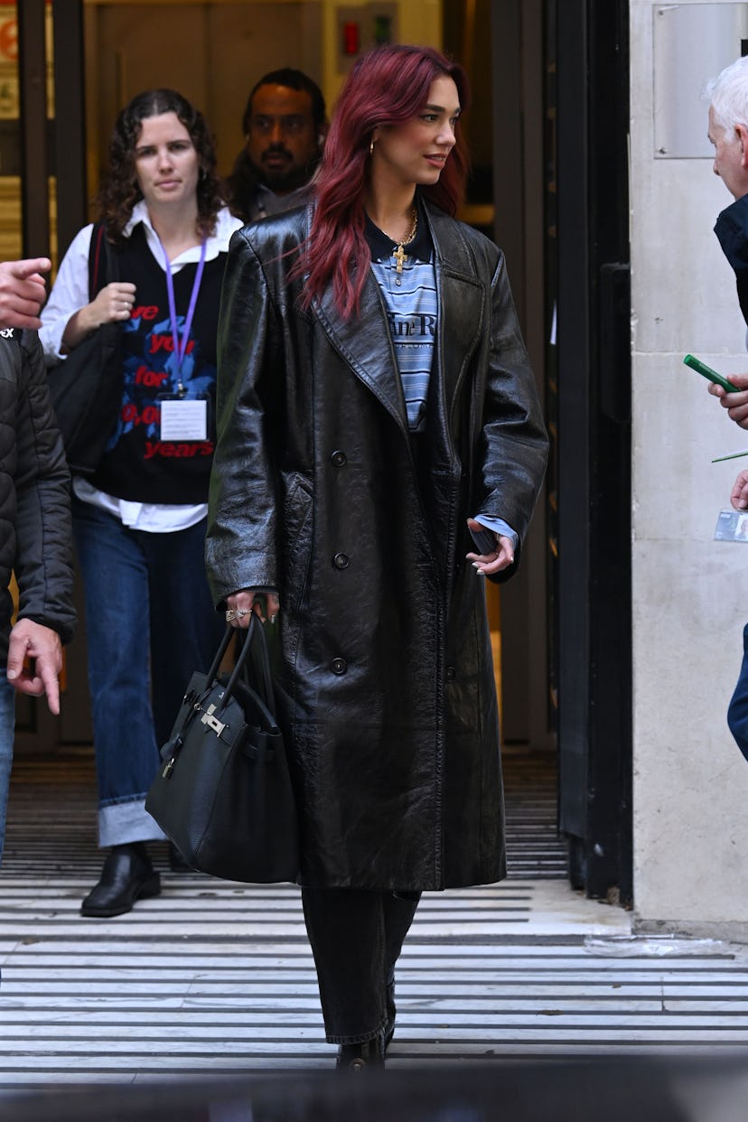 Dua Lipa wears a Hermès Birkin with a leather trench coat and a polo shirt