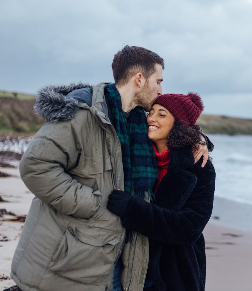 A shot of a couple embracing whilst on a beach walk at Newton-by-the-Sea in Northumberland, North Ea...