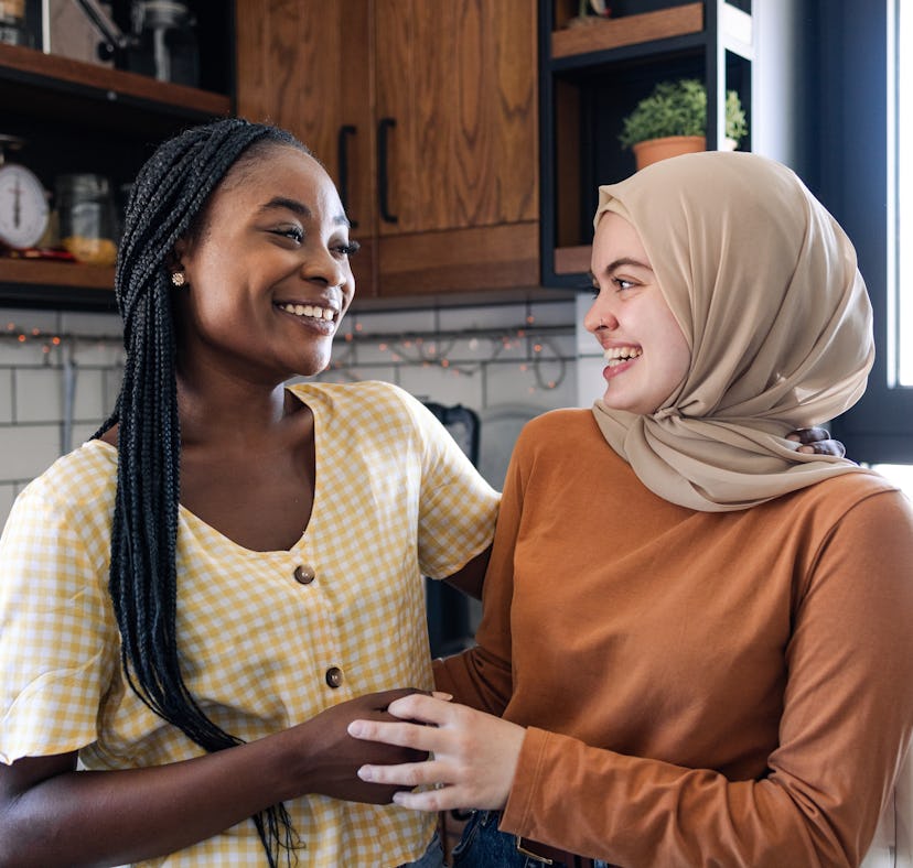 two friends smile at one another while standing in the kitchen, consider why February 10, 2024 will ...