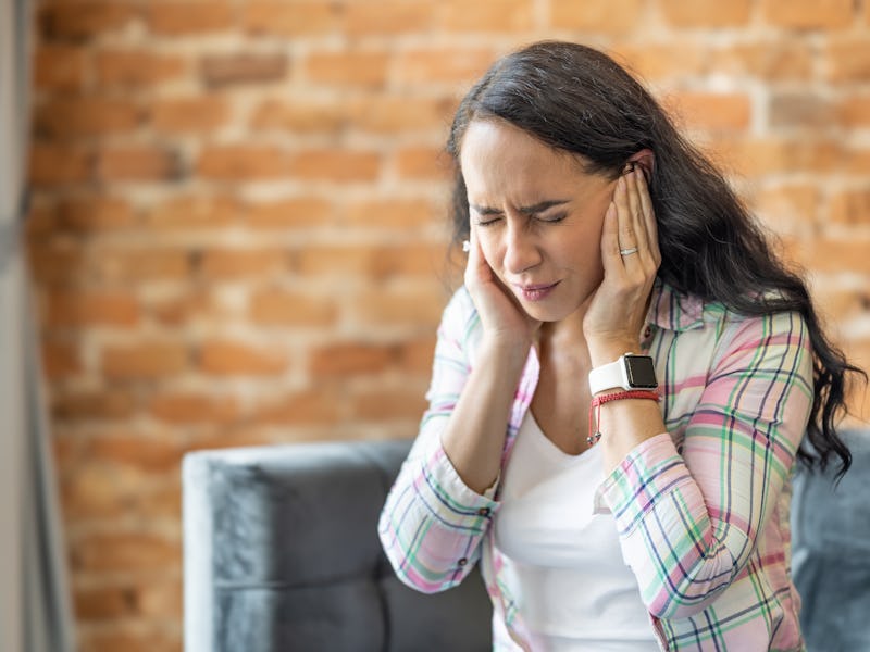 Young woman have headache migraine stress or tinnitus - noise whistling in her ears. A woman suffers...