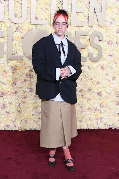 Billie Eilish wears a button-down, blazer, and khaki skirt to the 2024 Golden Globe Awards.