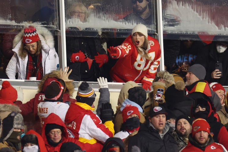 Taylor Swift celebrates with fans, while wearing a custom Travis Kelce Kansas City Chiefs puffer coa...