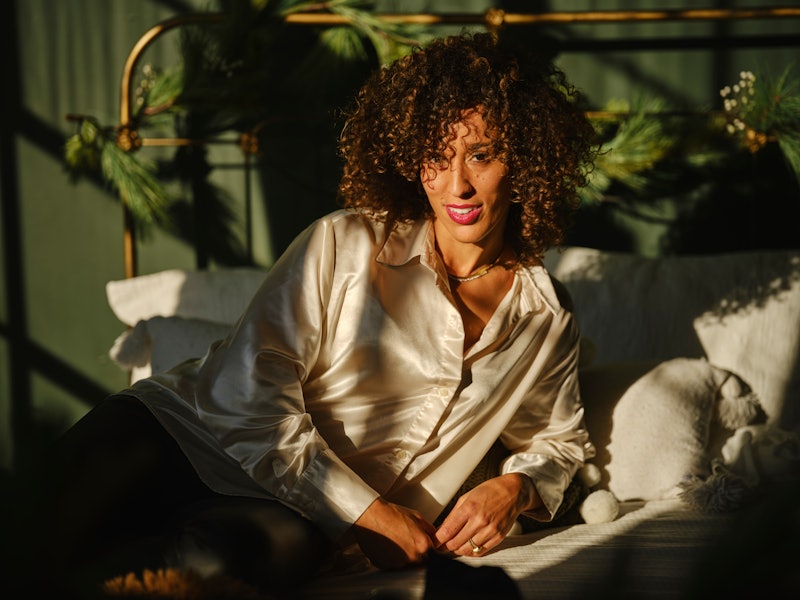 A multiracial woman relaxing on a sunlit bed.