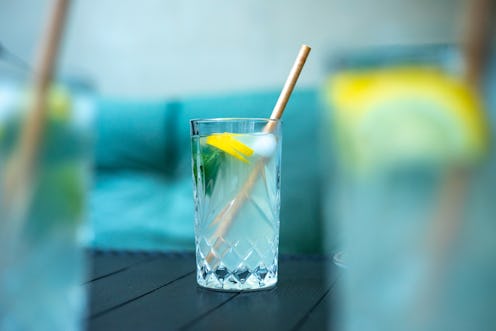Photo of three glasses of alcohol cocktails with lemon slices and straws standing on dark table in r...