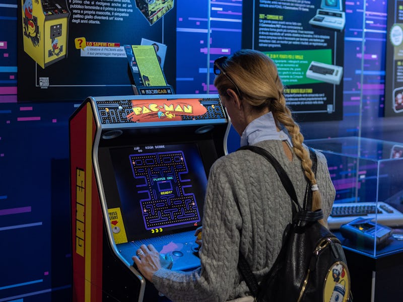 MILAN, ITALY - NOVEMBER 25: A woman plays a vintage Pac-Man video game during the Milan Games Week &...