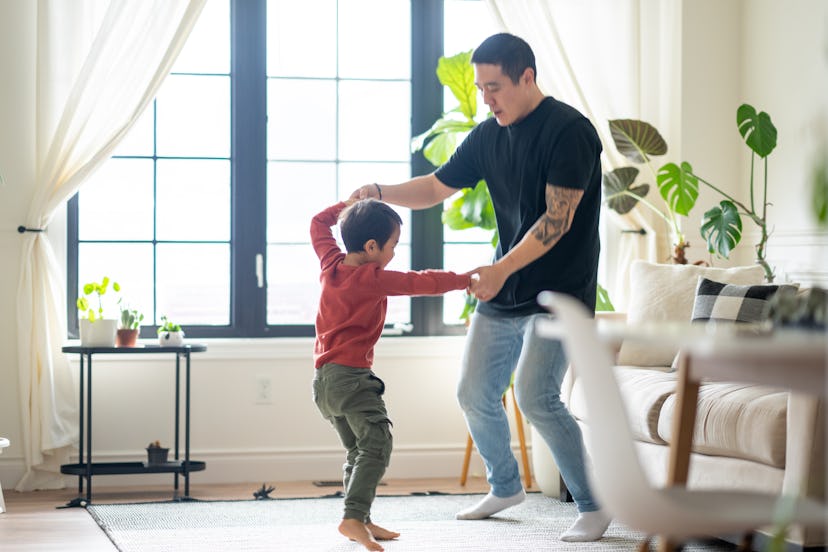 A sweet young boy of Asian decent is seen dancing in the living room with his Dad on a sunny afterno...