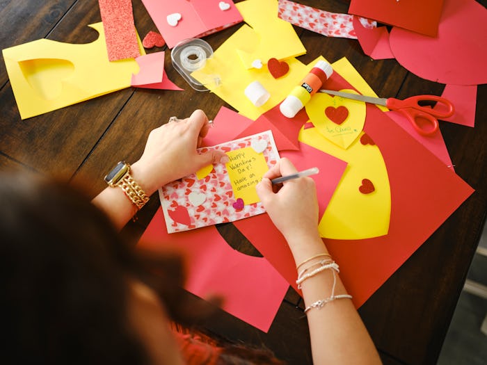 A hispanic family making Valentines Day cards together in a home.