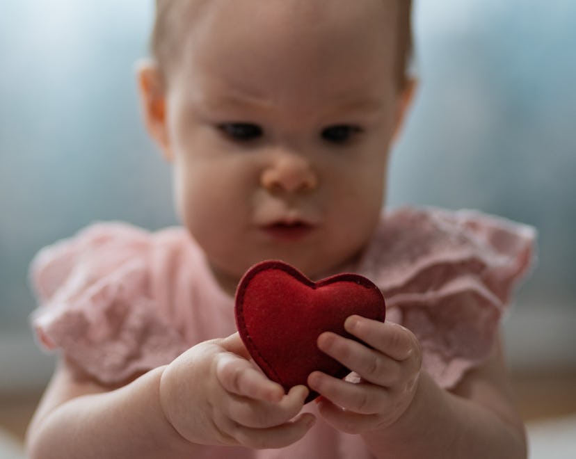 A cute baby girl dressed in pink is enjoying a Valentines day photo shoot