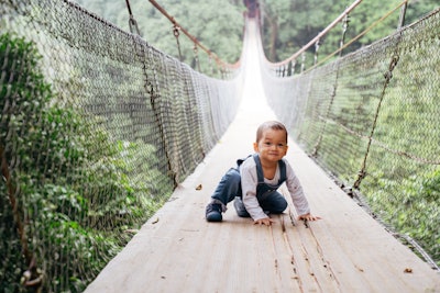 cute baby learning walking on the suspension bridge
