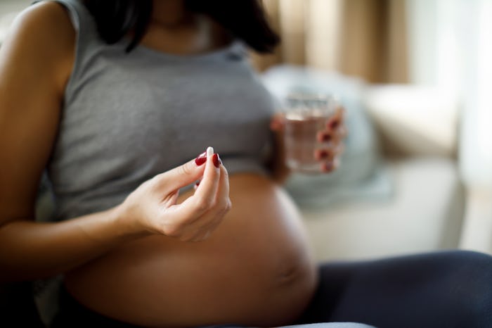 Pregnant woman taking pill at home, in a story answering the question, can you take paxlovid while p...
