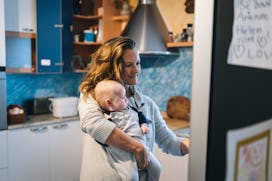 She is getting something from fridge while holding baby